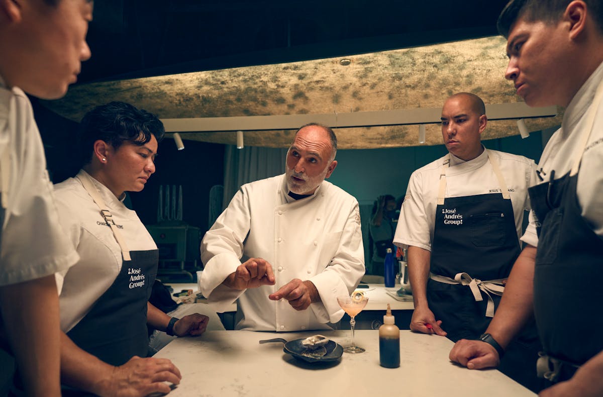 Jose Andres et al. standing on top of a cutting board with a cake